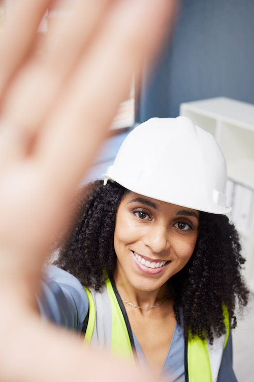 Woman technician in safety vest smiling