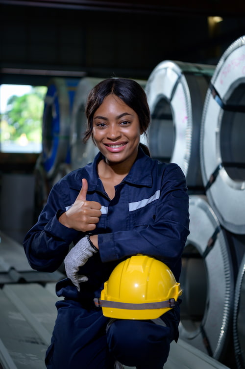 Woman technician in PPE smiling, giving a thumbs up